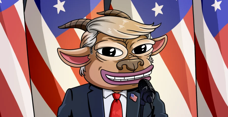A brown goat with swept blond hair, a navy suit, red tie and flag pin, smiling at a microphone in front of American flags.